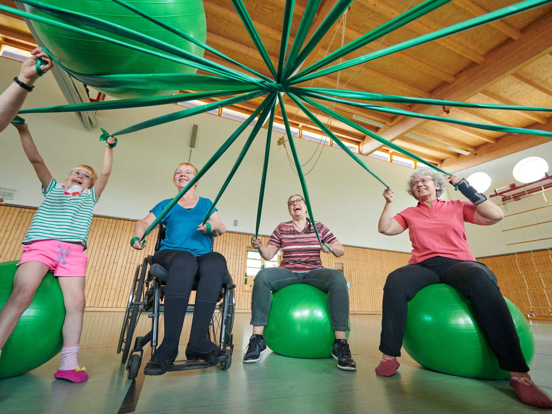 Menschen bei Gymnastik auf grünem Gymnastikball sitzend