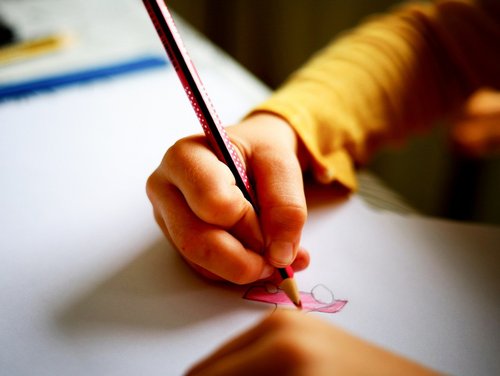 Ein Kind malt in der Schule mit einem Buntstift.